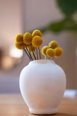 a white vase with yellow flowers in it on a table at Casa Bustamante Hotel Boutique in Cartagena de Indias
