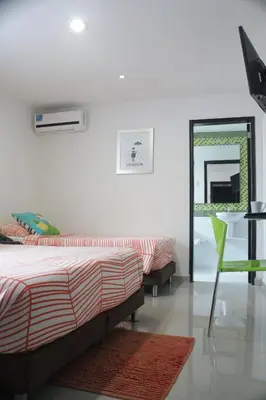 a bedroom with two beds and a table and a mirror at Hotel Golden House in Barranquilla