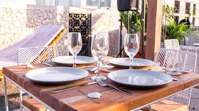 a wooden table with plates and wine glasses on it at Soy Local Insignia in Cartagena de Indias