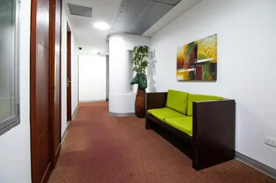 a green couch in a hallway with a plant at Atlantic Garden Hotel in Barranquilla