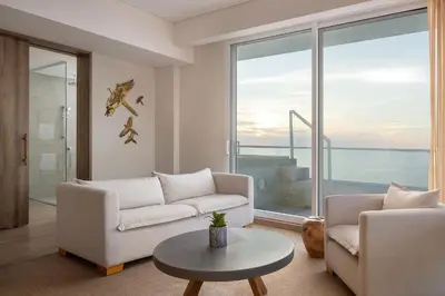 a living room with white furniture and a large window at Santa Marta Marriott Resort Playa Dormida in Santa Marta