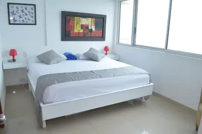 a white bedroom with a white bed and two windows at palmetto frente al mar in Cartagena de Indias