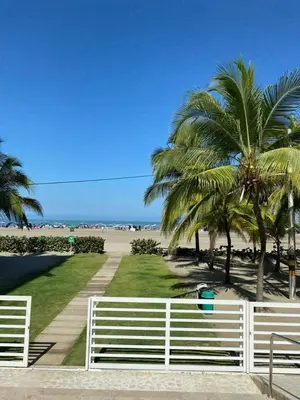 a white fence next to a beach with palm trees at Cartagena Morros playa edificio frente al mar 1 in Cartagena de Indias
