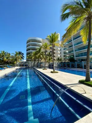 a swimming pool with palm trees and a building at Cartagena Morros playa edificio frente al mar 1 in Cartagena de Indias