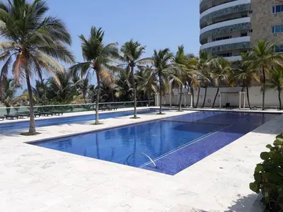 a swimming pool with palm trees and a building at Cartagena Morros playa edificio frente al mar 1 in Cartagena de Indias
