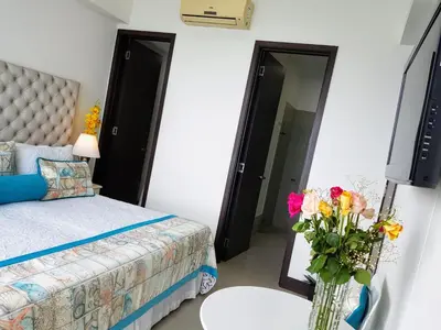 a bedroom with a bed and a vase of flowers at Encantador apartamento frente a la playa in Cartagena de Indias