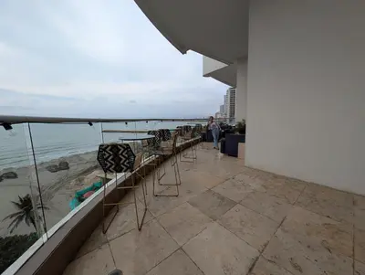 a row of chairs on a balcony overlooking the ocean at Encantador apartamento frente a la playa in Cartagena de Indias