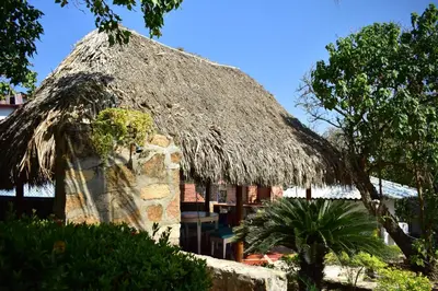 a hut with a thatched roof and a palm tree at Casa en Santa Veronica Atlantico in Santa Veronica