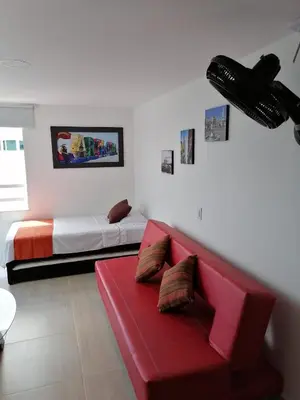 a living room with a red couch and a bed at Ocean blue Ed Conquistador in Cartagena de Indias
