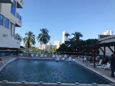a large swimming pool with chairs and palm trees at Ocean blue Ed Conquistador in Cartagena de Indias