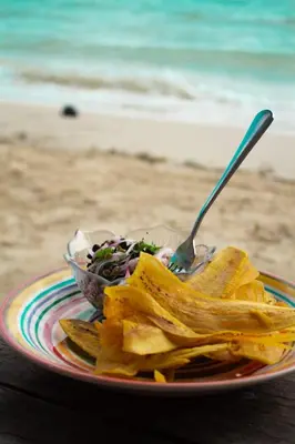a plate of food with chips and a salad with a fork at Canto de Caracola in Rincón