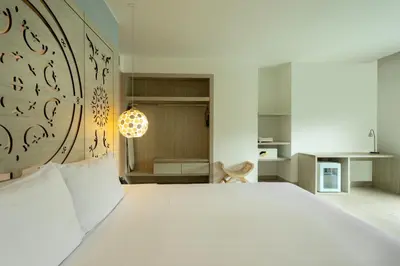 a bedroom with a large white bed and a kitchen at Grand Sirenis Cartagena in Cartagena de Indias