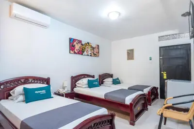 a room with two beds and a chair in it at Ayenda 1309 Villa Dilia in Barranquilla
