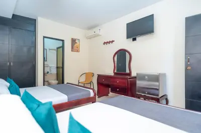 a bedroom with two beds and a desk and a tv at Ayenda 1309 Villa Dilia in Barranquilla