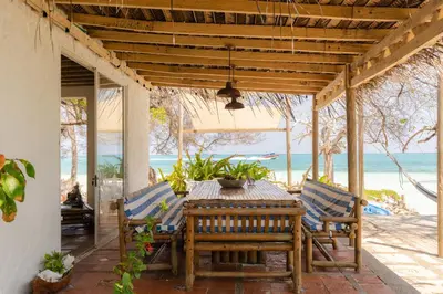 a wooden table and chairs on a patio with the beach at Casa Tinti in Tintipan Island