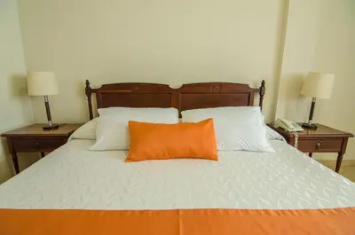 an orange pillow sits on a bed with two night stands at Hotel Majestic in Barranquilla