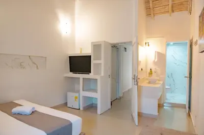 a white room with a bed and a sink and a television at Casa Amanzi Cartagena by Bernalo Hotels in Cartagena de Indias