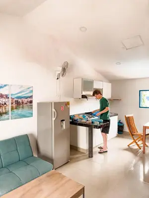 a man standing at a table in a kitchen with a refrigerator at Casa del Puerto Hostel & Suites in Cartagena de Indias