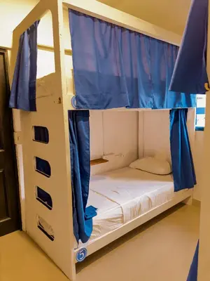 a bunk bed with blue curtains in a room at Casa del Puerto Hostel & Suites in Cartagena de Indias