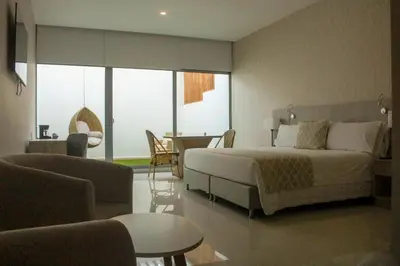 a bedroom with a bed and a living room at Hotel Dorado Plaza Alto Prado in Barranquilla