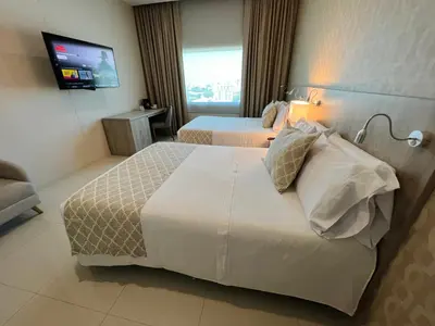 a hotel room with two beds and a television at Hotel Dorado Plaza Alto Prado in Barranquilla