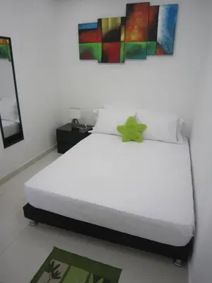 a bedroom with a white bed with a painting on the wall at Hotel Valmar in Cartagena de Indias
