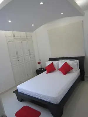a bedroom with a white bed with red pillows at Hotel Valmar in Cartagena de Indias