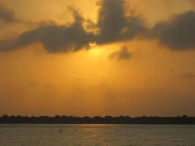 a sunset over the water with the sun hiding behind a cloud at Hotel Valmar in Cartagena de Indias