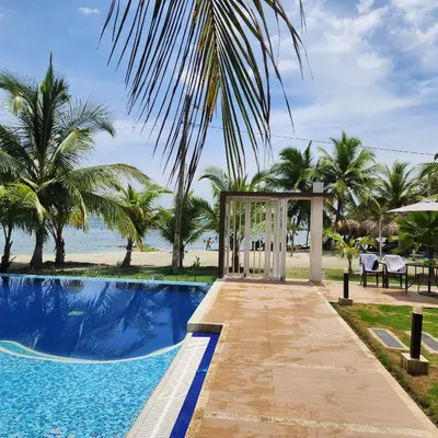 a gazebo next to a swimming pool with palm trees at Costa Serena Casa 3 in Coveñas