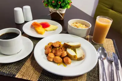 a table with two plates of food and a cup of coffee at Hotel Avexi Suites By GEH Suites in Cartagena de Indias