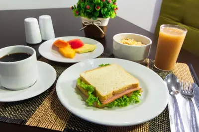 a table with a sandwich and a cup of coffee and fruit at Hotel Avexi Suites By GEH Suites in Cartagena de Indias