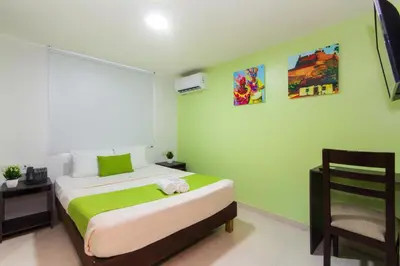 a bedroom with a bed and a chair and a television at Hotel Avexi Suites By GEH Suites in Cartagena de Indias