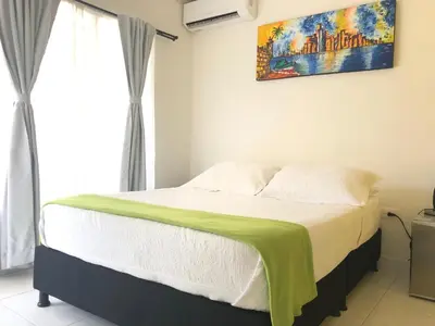 a bedroom with a bed with a green blanket on it at Hotel Balcones de Bocagrande in Cartagena de Indias