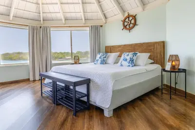 a bedroom with a large bed and two windows at Fragata Island House in Isla Grande