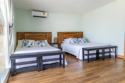 two beds in a room with wooden floors at Fragata Island House in Isla Grande