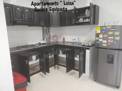 a kitchen with black cabinets and a refrigerator at Apartamentos LUISA in Coveñas