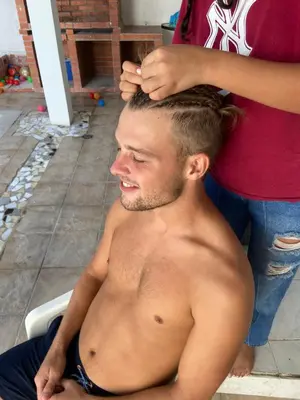 a shirtless man getting his hair cut by a woman at Hotel Blue Diamond House in Cartagena de Indias