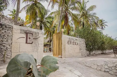 a building with a wooden gate and palm trees at Éteka Slow Beach Hotel Adults Only in Cartagena de Indias