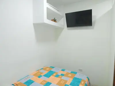 a bedroom with a bed and a tv on a wall at STUDIO DELFINES / BOCAGRANDE in Cartagena de Indias