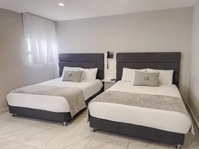 two beds in a hotel room with white walls at Hotel OR Suites in Barranquilla