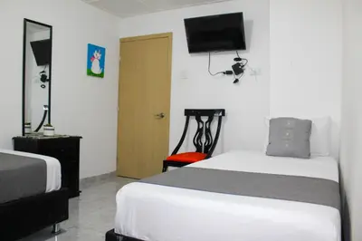 a bedroom with two beds and a television on the wall at Hotel Poblado Suite in Barranquilla