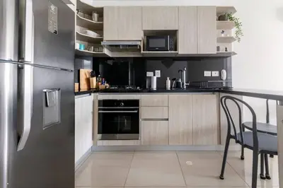 a kitchen with a stainless steel refrigerator and a table at Cómodo moderno apto en Bocagrande a 2' de la playa in Cartagena de Indias