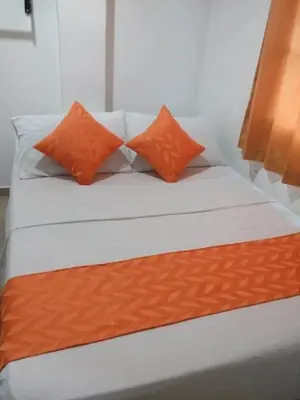a bed with two orange pillows on top of it at Hotel Torres del Parque No1 in Soledad
