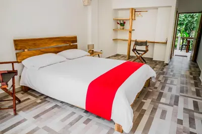 a bedroom with a large white bed with a red blanket at Hotel Restaurante Selva Negra in Turbaco