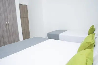 a white bedroom with a bed and a chair at Hotel Ayenda House Concepción 1317 in Barranquilla