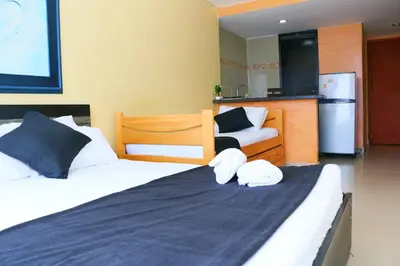 a bedroom with two beds and a kitchen with a refrigerator at Loft sea view 19C air and wifi in Cartagena de Indias