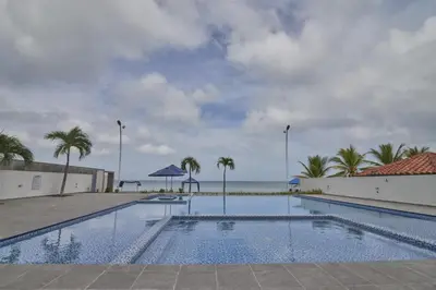 a swimming pool with palm trees and the ocean at Mágico Apartamento Frente al Mar 3 Habitaciones PV21 in Coveñitas