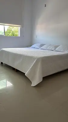a bed in a white bedroom with a window at Mágico Apartamento Frente al Mar 3 Habitaciones PV21 in Coveñitas
