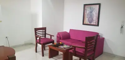 a living room with a purple couch and two chairs at Hotel Torre del Prado in Barranquilla