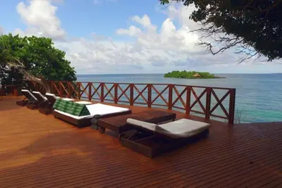 a deck with lounge chairs and a view of the ocean at Isla Única- Islas del Rosario in Isla Grande